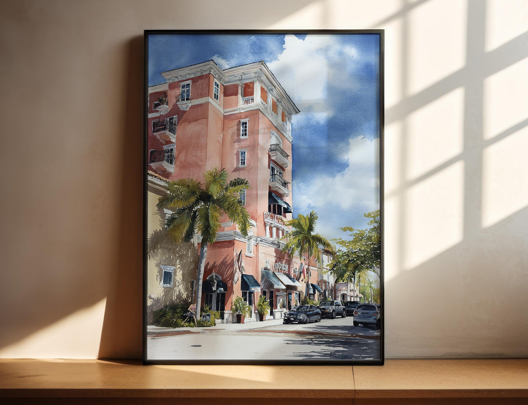 Watercolor Naples historic hotel wall art in a black frame featuring elegant palm-lined architecture and classic Florida streetscape, a charming coastal print.