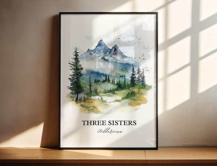 Three Sisters Wilderness watercolor wall art in a black frame featuring majestic alpine peaks rising above evergreen forests in soft blue and green tones.