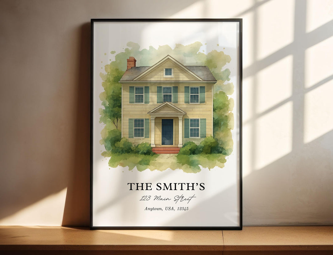Custom watercolor house portrait print example featuring a two-story yellow home with green shutters surrounded by trees, personalized with a family name and address below, displayed in a black vertical frame.