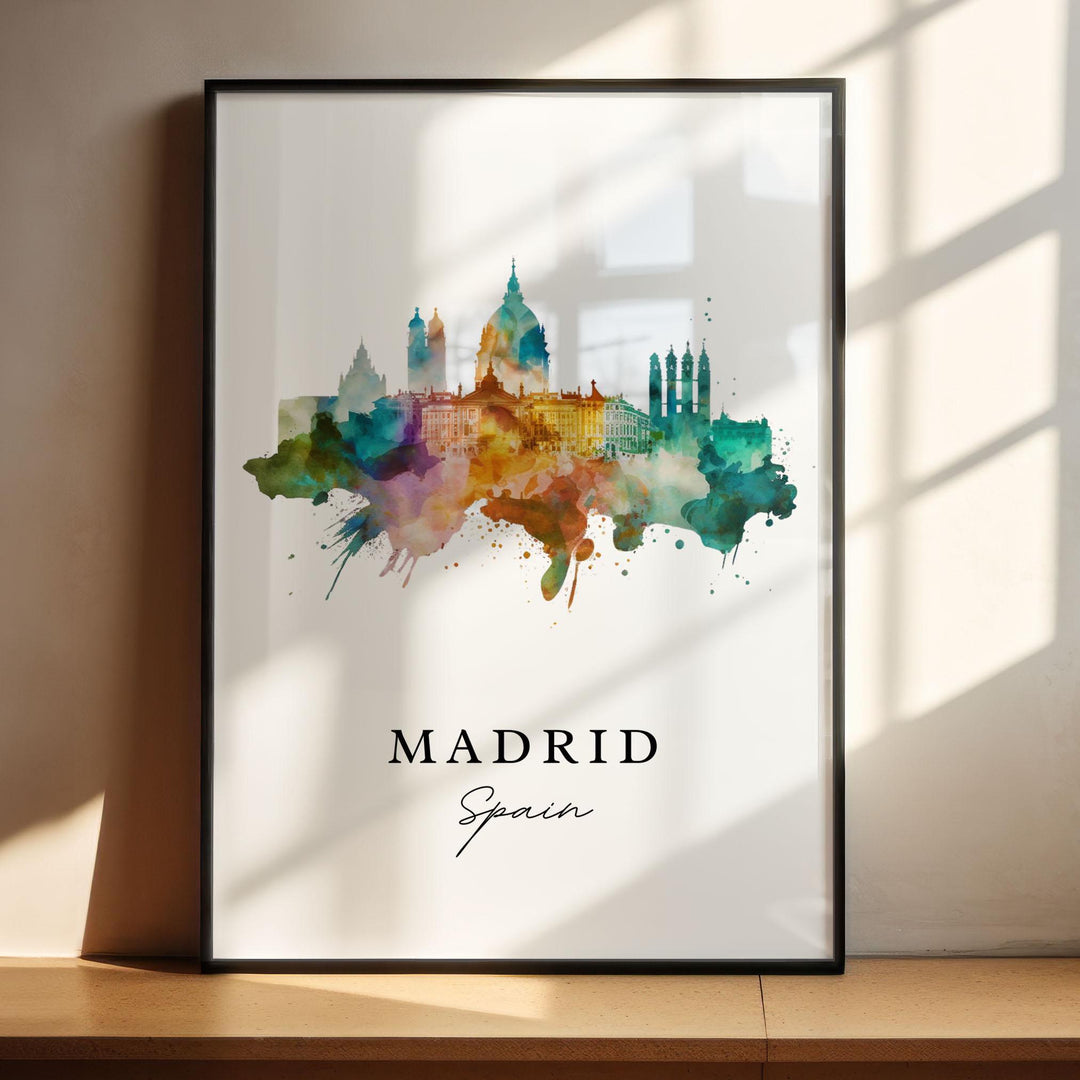 Abstract watercolor travel art print of the Madrid, Spain city skyline silhouette featuring iconic architectural landmarks like the Almudena Cathedral dome in a vibrant multi-colored splash design, displayed in a black frame with window shadow lighting.