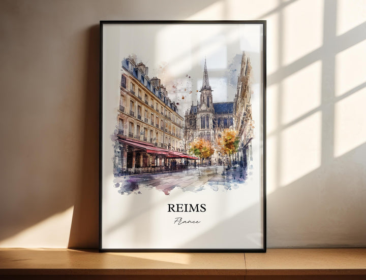 Watercolor travel art print of Reims, France featuring a charming city street with a sidewalk cafe under a red awning, leading toward a towering historic Gothic cathedral in the background, displayed in a black frame with window shadow lighting.